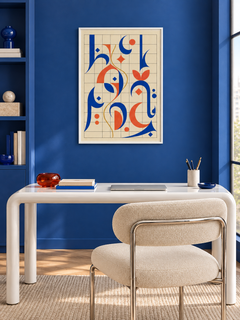Grid Letter: cobalt and orange Arabic-inspired forms on a geometric grid, displayed in a slim white frame in a styled interior.