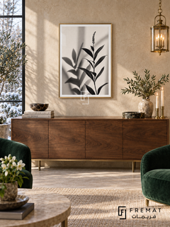 Botanical Shadow by FREMAT: botanical leaves and shadows in a gold PVC frame with a printed white border, displayed in a styled interior.
