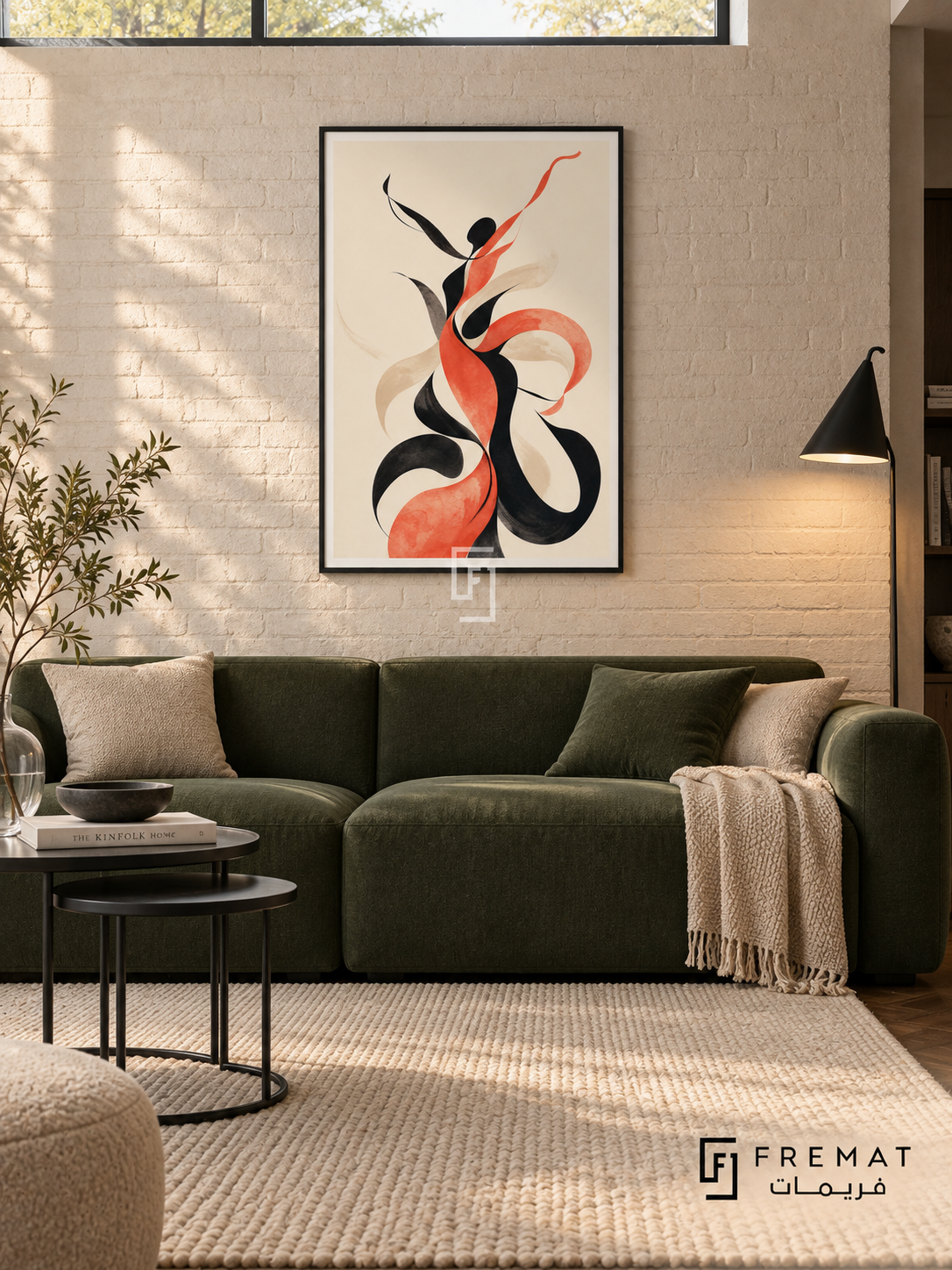 Figure Dance by FREMAT in a matte black PVC frame with a flat white printed border. Architect apartment: ivory brick wall, 160cm forest-green low sofa, black steel nesting tables left, cream loop rug on dark parquet, overhead clerestory glow plus a slim conical floor lamp, quiet glass vase with one branch.