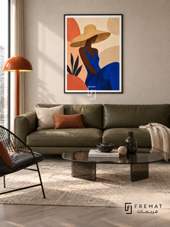 Sun Hat by FREMAT in a matte black PVC frame with a flat white printed border. Fashion apartment lounge: pale oatmeal fabric wall, 160cm olive leather sofa below artwork, black wire accent chair at left, low oval smoked-glass table, grey parquet, cool even daylight and sculptural orange floor lamp.