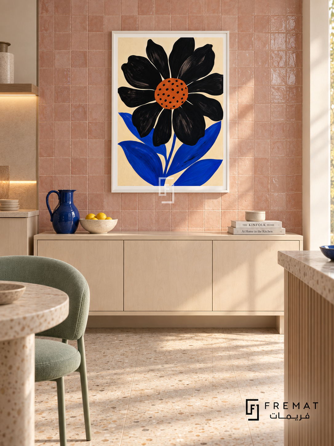 Graphic Flower by FREMAT in a satin white PVC frame with a flat white printed border. Light creative kitchen lounge: warm blush zellige tiled wall with subtle irregular glaze, 150cm white maple cabinet below art, mint upholstered chair left, cream terrazzo floor, diffuse afternoon light and simple cobalt pitcher.