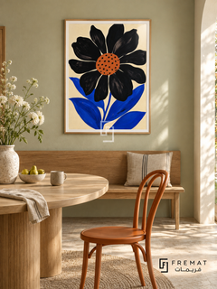 Graphic Flower by FREMAT in a light natural wood PVC frame with a flat white printed border. Florist apartment dining nook: pale pistachio chalk wall, 145cm oak bench, small oval ash dining table in foreground left, orange bentwood chair right, pale stone floor, morning sunshine and a small loose arrangement of white stems.