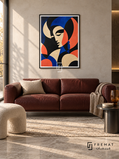 Statement Portrait by FREMAT in a matte black PVC frame with a flat white printed border. Modern gallery sitting room: pale bone concrete wall, 160cm oxblood leather sofa, blackened steel side table right, cream curved stool left, grey travertine floor, side-lit afternoon atmosphere and amber tumbler vase.