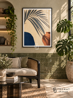 Palm Shadow NAT05 by FREMAT in a slim matte black PVC frame, with an even white printed border, subtle glazing reflections and furniture showing scale.