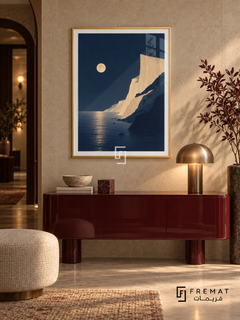 Moonlit Coast NAT13 by FREMAT in a slim champagne gold PVC frame, with an even white printed border, subtle glazing reflections and furniture showing scale.
