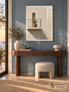 Sunlit Balcony (PLC07) framed architectural wall art with a champagne gold PVC frame, flat white paper border and glass reflection. Luxury coastal entry, subdued blue wall panels, walnut demilune console 150cm.