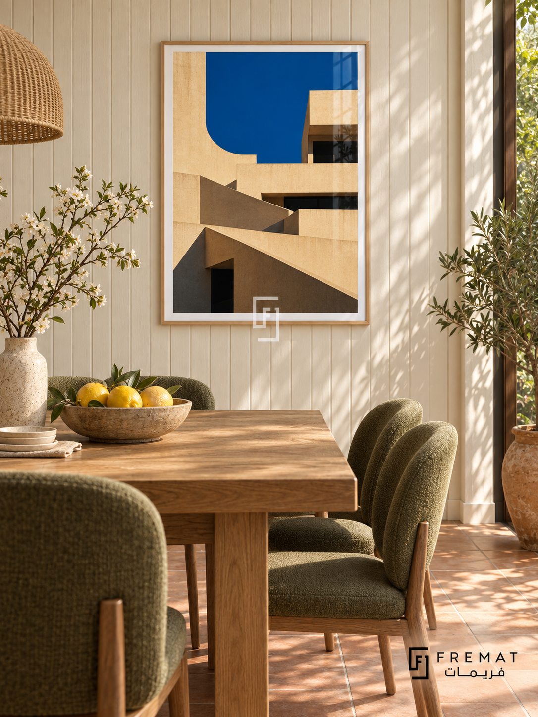 Terrace Forms (PLC09) framed architectural wall art with a light wood-grain PVC frame, flat white paper border and glass reflection. Sunlit garden dining nook, ivory grooved wall, oak square table 140cm.