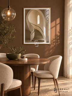 Stone Stairwell (PLC14) framed architectural wall art with a champagne gold PVC frame, flat white paper border and glass reflection. Elegant dining nook, warm dark clay wall, walnut round table 145cm.