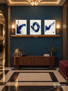 Cobalt Current shelf set, gold frames: three 30 x 40 cm artworks with equal 2 cm borders, honey wood 130 cm shelf and two upward warm sensor lamps. Art Deco foyer at night.