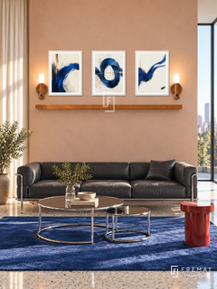 Cobalt Current shelf set, white frames: three 30 x 40 cm artworks with equal 2 cm borders, honey wood 130 cm shelf and two upward warm sensor lamps. Bauhaus living room in morning sunlight.
