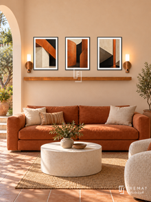 Burnt Orange Architecture shelf set in black frames, three 30 x 40 cm artworks with 2 cm borders, honey wood shelf and two sensor lamps. Spanish contemporary lounge in morning light.
