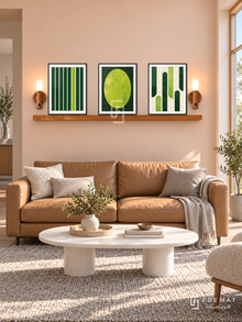 FREMAT SH-ABS24-BLK shelf set, three 30 x 40 cm artworks with 2 cm white mats, honey wood shelf and two upward sensor lamps. Morning Scandinavian peach lounge, pale peach wall, tan leather sofa, white oval table, wool grey rug, wide window right.