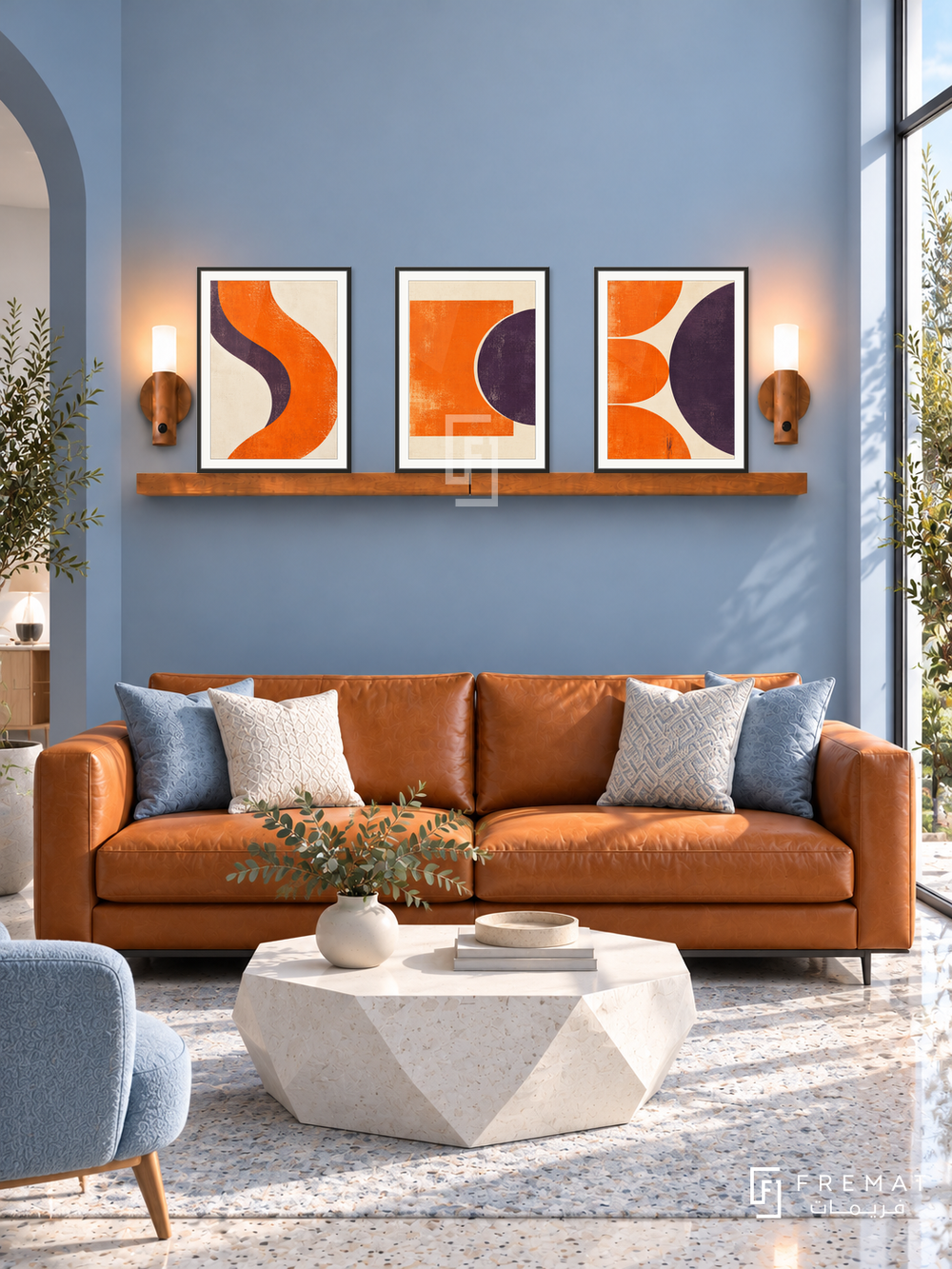 FREMAT SH-ABS28-BLK shelf set, three 30 x 40 cm artworks with 2 cm white mats, honey wood shelf and two upward sensor lamps. Morning modern ice blue lounge, blue wall, orange leather couch, white geometric table, pale terrazzo floor, narrow tall window right.