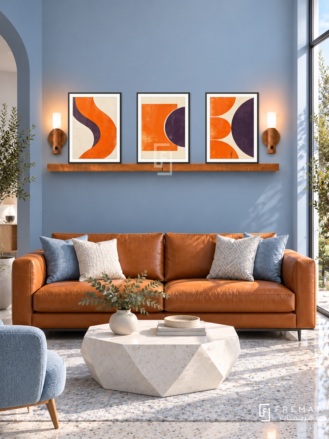 FREMAT SH-ABS28-BLK shelf set, three 30 x 40 cm artworks with 2 cm white mats, honey wood shelf and two upward sensor lamps. Morning modern ice blue lounge, blue wall, orange leather couch, white geometric table, pale terrazzo floor, narrow tall window right.