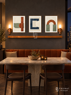 FREMAT SH-ABS30-WOD shelf set, three 30 x 40 cm artworks with 2 cm white mats, honey wood shelf and two upward sensor lamps. Night elegant modern dining corner, slate wall, warm rust banquette, cream marble rectangular table, dark wooden chairs, dark parquet, night window right.
