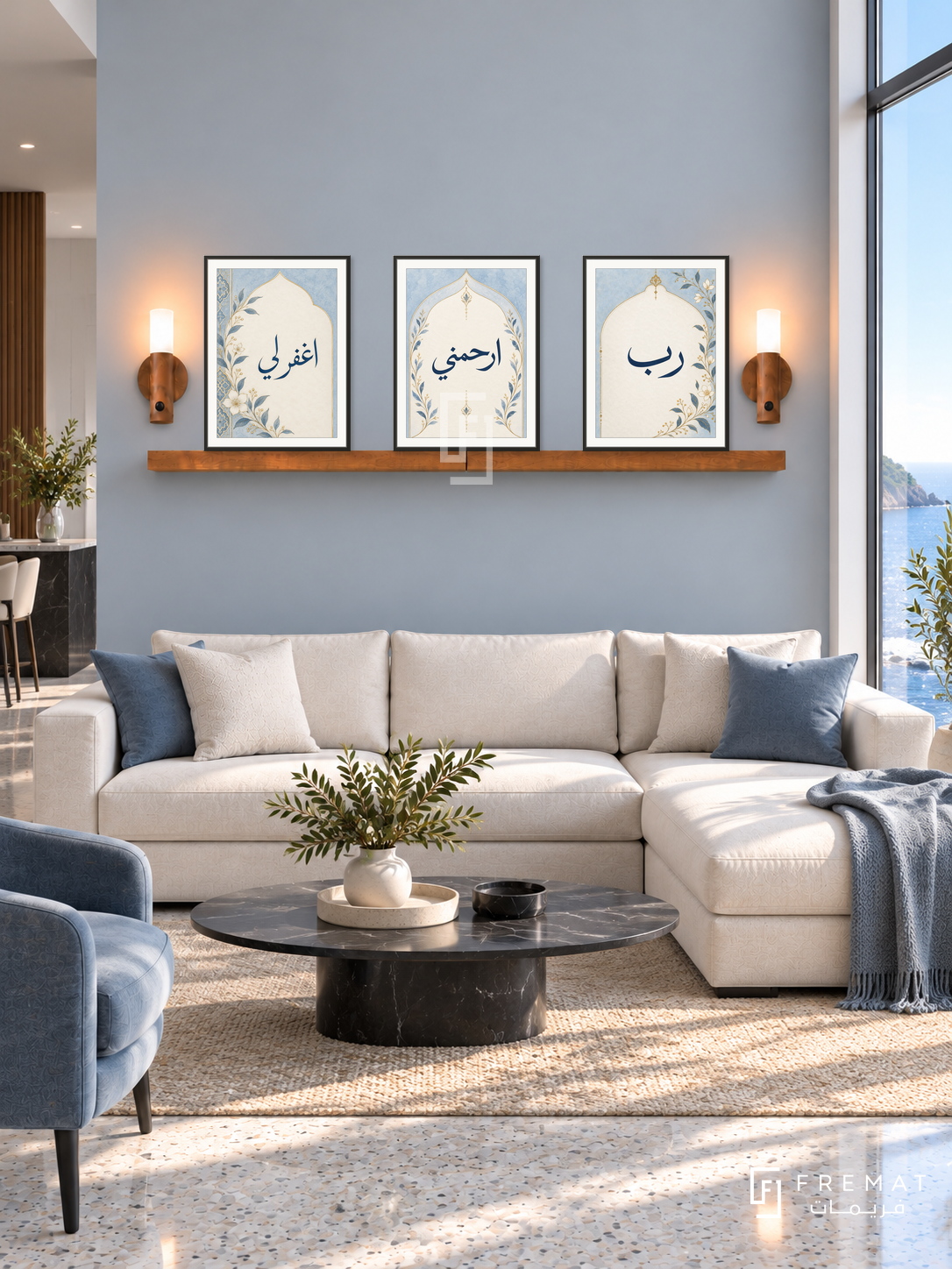 FREMAT Blue Prayer shelf set with three 30 x 40 cm frames, 2 cm white borders, honey wood shelf and two warm sensor lamps. Morning modern ocean-blue reception, muted blue-grey wall, cream modular sectional, black oval marble table, pale terrazzo floor, large seafront window right.