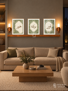 FREMAT Palm Cartouche shelf set with three 30 x 40 cm wooden texture frames, 2 cm white borders, honey wood shelf and two warm sensor lamps. Night organic modern living room, moss grey plaster wall, tan sofa, low square oak table, cream textured rug, amber niche far left.