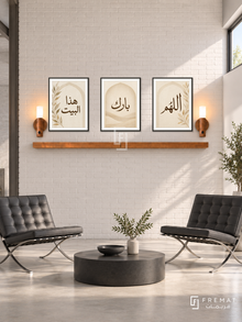FREMAT Pearl Home shelf set with three 30 x 40 cm black frames, 2 cm white borders, honey wood shelf and two warm sensor lamps. Morning industrial minimalist pearl reception, broad off-white brick wall, two charcoal Barcelona-style leather chairs rather than a sofa, low black circular coffee table, smooth pale concrete flooring, horizontal high window on far right. Completely different room architecture and furniture from reference.