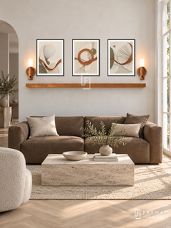 FREMAT Woven Light shelf set with three 30 x 40 cm black frames, 2 cm white borders, honey wood shelf and two warm sensor lamps. Morning Belgian minimalist reception, chalk white limewash wall, tobacco brown linen sofa with low square arms, travertine block coffee table, pale herringbone oak floor, bright French window right.