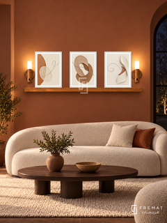 FREMAT Earth And Thread shelf set with three 30 x 40 cm white frames, 2 cm white borders, honey wood shelf and two warm sensor lamps. Night refined terracotta living room, soft burnt clay wall, white curved boucle sofa, dark wood oval coffee table, cream wool rug, dark arched window right.