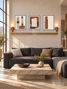 FREMAT Desert Textiles shelf set with three 30 x 40 cm black frames, 2 cm white borders, honey wood shelf and two warm sensor lamps. Morning modern desert loft, pale sandstone wall, charcoal linen sectional, rough beige stone coffee table, warm concrete floor, tall sunny industrial glazing left.
