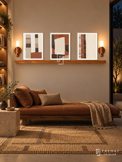 FREMAT Desert Textiles shelf set with three 30 x 40 cm wooden texture frames, 2 cm white borders, honey wood shelf and two warm sensor lamps. Night organic minimalist library, warm sand wall, low walnut daybed with cinnamon cushions, square stone side table, woven geometric rug, dark courtyard opening right.