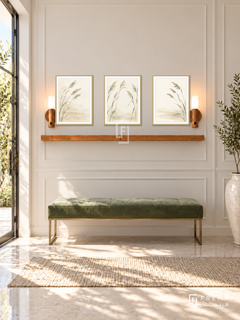 FREMAT Quiet Reeds shelf set with three 30 x 40 cm gold frames, 2 cm white borders, honey wood shelf and two warm sensor lamps. Morning elegant botanical entrance, pale ivory panelled wall, soft green velvet bench with brass legs, cream stone floor, sunlit doorway left, tall ceramic vase far right.