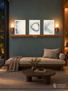 FREMAT Woven Water shelf set with three 30 x 40 cm wooden texture frames, 2 cm white borders, honey wood shelf and two warm sensor lamps. Night Japanese reading room, muted blue-green plaster wall, low walnut daybed with oatmeal cushions, round dark wood table, woven grey rug, dark courtyard glazing left, warm wooden alcove on right.
