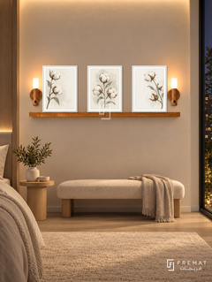 FREMAT Wild Cotton shelf set with three 30 x 40 cm white frames, 2 cm white borders, honey wood shelf and two warm sensor lamps. Night soft minimalist bedroom corner, warm ivory plaster wall, cream fabric bench, pale oak pedestal table, cream rug, dark full height window right, warm indirect ceiling glow.