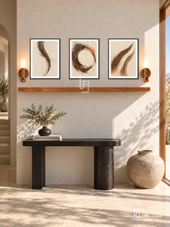 FREMAT Sand Script shelf set with three 30 x 40 cm black frames, 2 cm white borders, honey wood shelf and two warm sensor lamps. Morning desert contemporary corridor, ivory rough plaster wall, black sculptural console, large low clay vessel, pale sandstone floor, sharp sunlight through doorway right.