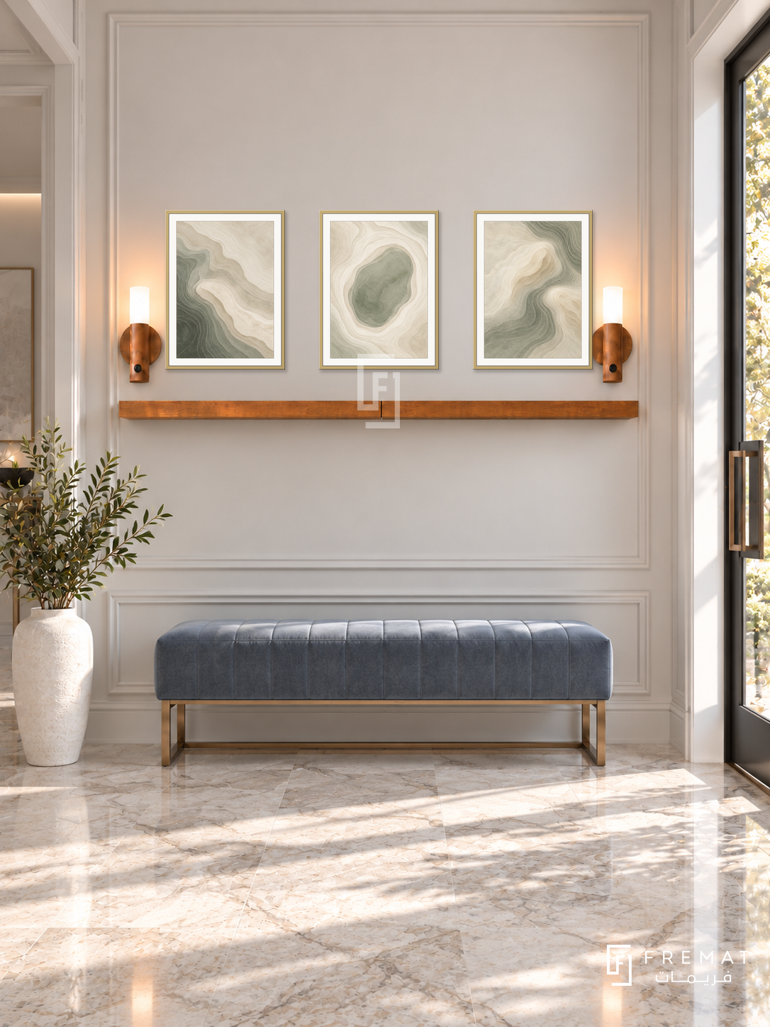 FREMAT Soft Topography shelf set with three 30 x 40 cm gold frames, 2 cm white borders, honey wood shelf and two warm sensor lamps. Morning refined contemporary entrance, pearl moulded wall, grey-blue velvet bench on bronze base, pale veined stone floor, sunny door right, tall white vase left.