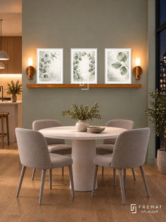 FREMAT Eucalyptus Mist shelf set with three 30 x 40 cm white frames, 2 cm white borders, honey wood shelf and two warm sensor lamps. Night Scandinavian apartment dining nook, mist sage wall, white round dining table with pale grey chairs, oak floor, dark window right and softly lit open kitchen far left.