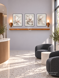FREMAT Pearl Bloom shelf set with three 30 x 40 cm black frames, 2 cm white borders, honey wood shelf and two warm sensor lamps. Morning minimalist facial clinic reception, soft lilac grey wall, charcoal rounded waiting chairs, white cylindrical table, pale terrazzo floor, sunny glass entrance right, restrained clean interior.