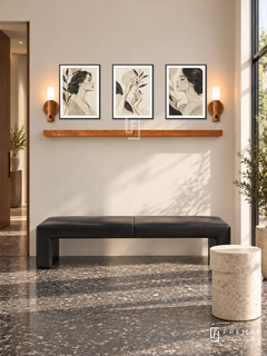 FREMAT Contour Muse shelf set with three 30 x 40 cm black frames, 2 cm white borders, honey wood shelf and two warm sensor lamps. Morning architectural beauty studio, warm ivory wall, black angular leather bench, pale cylindrical stone table, charcoal terrazzo floor, bright shopfront right, slim doorway left.