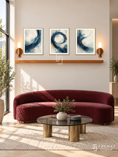 FREMAT Forward Current shelf set with three 30 x 40 cm gold frames, 2 cm white borders, honey wood shelf and two warm sensor lamps. Morning boutique consulting office, cream flat display wall, burgundy velvet curved bench, round smoked glass table with brass feet, pale oak herringbone floor, tall sunny window left.