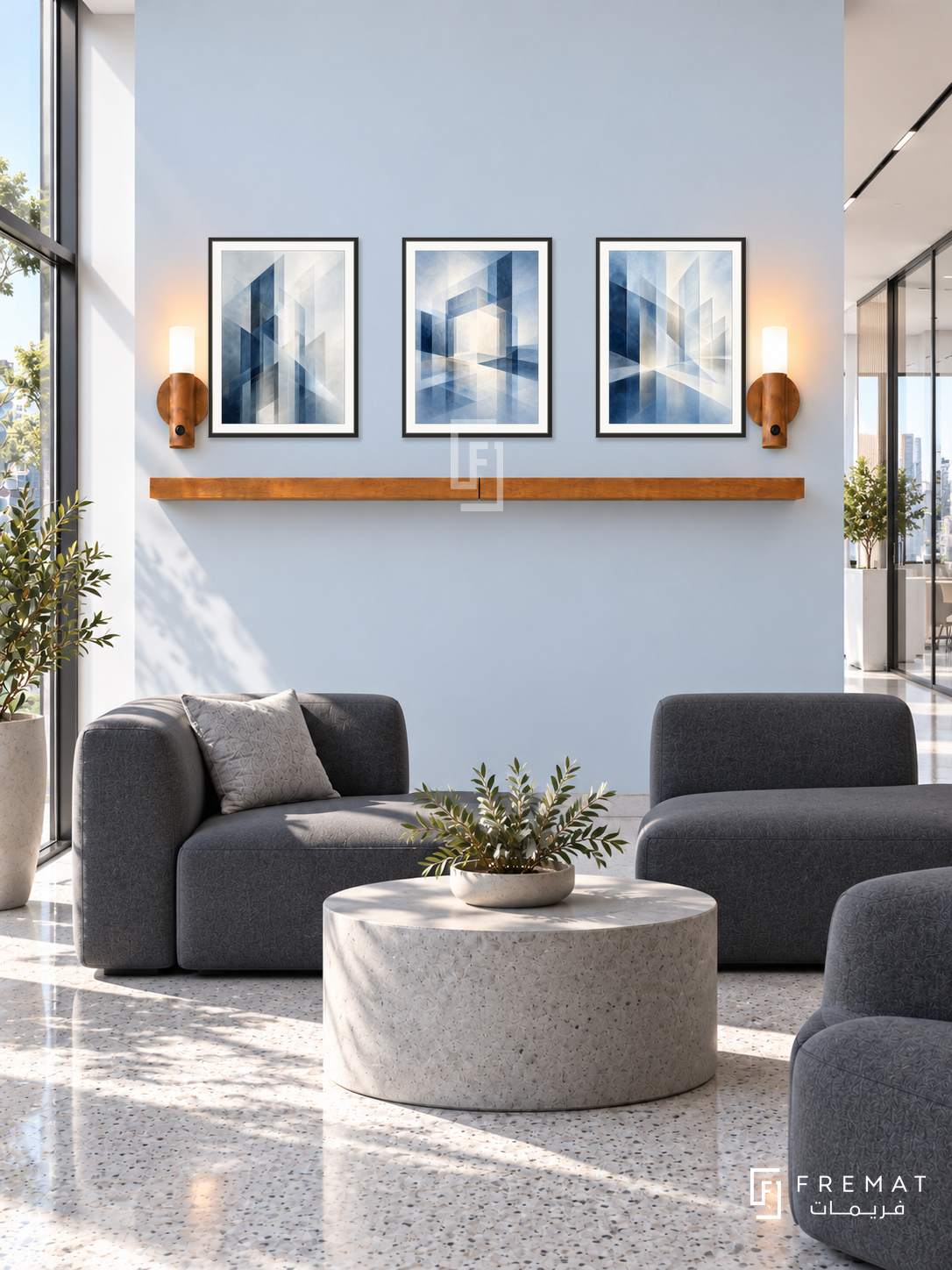 FREMAT Blueprints Of Light shelf set with three 30 x 40 cm black frames, 2 cm white borders, honey wood shelf and two warm sensor lamps. Morning contemporary technology office lobby, very pale blue display wall, graphite modular seating, cylindrical concrete table, fine grey terrazzo floor, bright glass corridor right, sunlit window left.