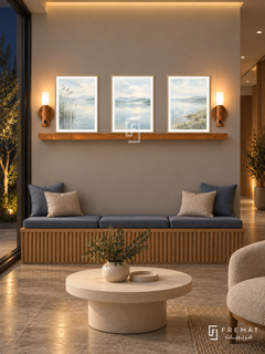 FREMAT Still Waters shelf set with three 30 x 40 cm wooden texture frames, 2 cm white borders, honey wood shelf and two warm sensor lamps. Night physiotherapy clinic waiting nook, warm grey display wall, oak slatted bench with blue cushions, low cream table, stone floor, dark courtyard window left, amber ceiling cove.