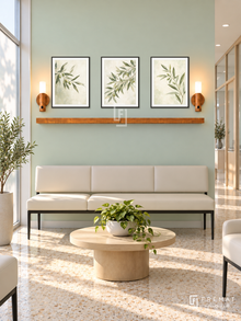 FREMAT Morning Leaves shelf set with three 30 x 40 cm black frames, 2 cm white borders, honey wood shelf and two warm sensor lamps. Morning family clinic reception, soft mint display wall, black-legged cream vinyl bench, rounded pale oak table, warm terrazzo floor, tall frosted sunny glazing left, glazed hallway right.