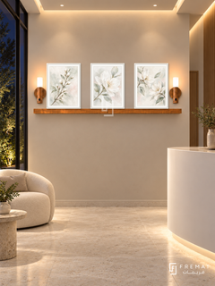 FREMAT White Blossom shelf set with three 30 x 40 cm white frames, 2 cm white borders, honey wood shelf and two warm sensor lamps. Night boutique medical reception, pearl beige display wall, white rounded counter lower right, ivory guest chair left, pale stone floor, dark garden glazing left, softly glowing ceiling slots.