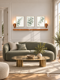 FREMAT Eucalyptus Air shelf set with three 30 x 40 cm gold frames, 2 cm white borders, honey wood shelf and two warm sensor lamps. Morning transitional sitting room, ivory wall with slim moulding, muted green curved sofa, brass oval coffee table, oak parquet, tall window right and double doors left.
