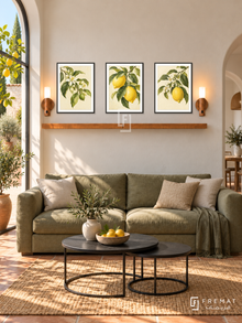 FREMAT Lemon Grove shelf set with three 30 x 40 cm black frames, 2 cm white borders, honey wood shelf and two warm sensor lamps. Morning bright Mediterranean lounge, pale cream wall, olive sofa, black nesting tables, terracotta floor, lemon courtyard through left glazing, rounded doorway right.
