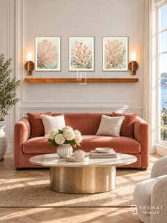 FREMAT Coral Garden shelf set with three 30 x 40 cm gold frames, 2 cm white borders, honey wood shelf and two warm sensor lamps. Morning elegant marine-inspired salon, ivory moulding, dusty coral velvet loveseat, champagne oval table, herringbone floor, bright window right.