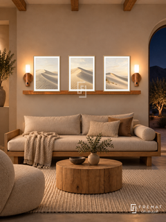 FREMAT Dune Silence shelf set with three 30 x 40 cm wooden texture frames, 2 cm white borders, honey wood shelf and two warm sensor lamps. Night adobe living room, clay beige wall, oak daybed with oatmeal cushions, round raw timber table, wool rug, exposed beams, dark desert view through arch right.