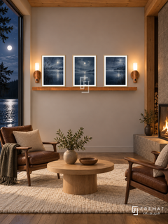 FREMAT Moonlit Lake shelf set with three 30 x 40 cm wooden texture frames, 2 cm white borders, honey wood shelf and two warm sensor lamps. Night Scandinavian lakeside cabin, pale taupe wall, walnut lounge chairs, round oak table, cream wool rug, moonlit water view left, timber ceiling and fireplace right.