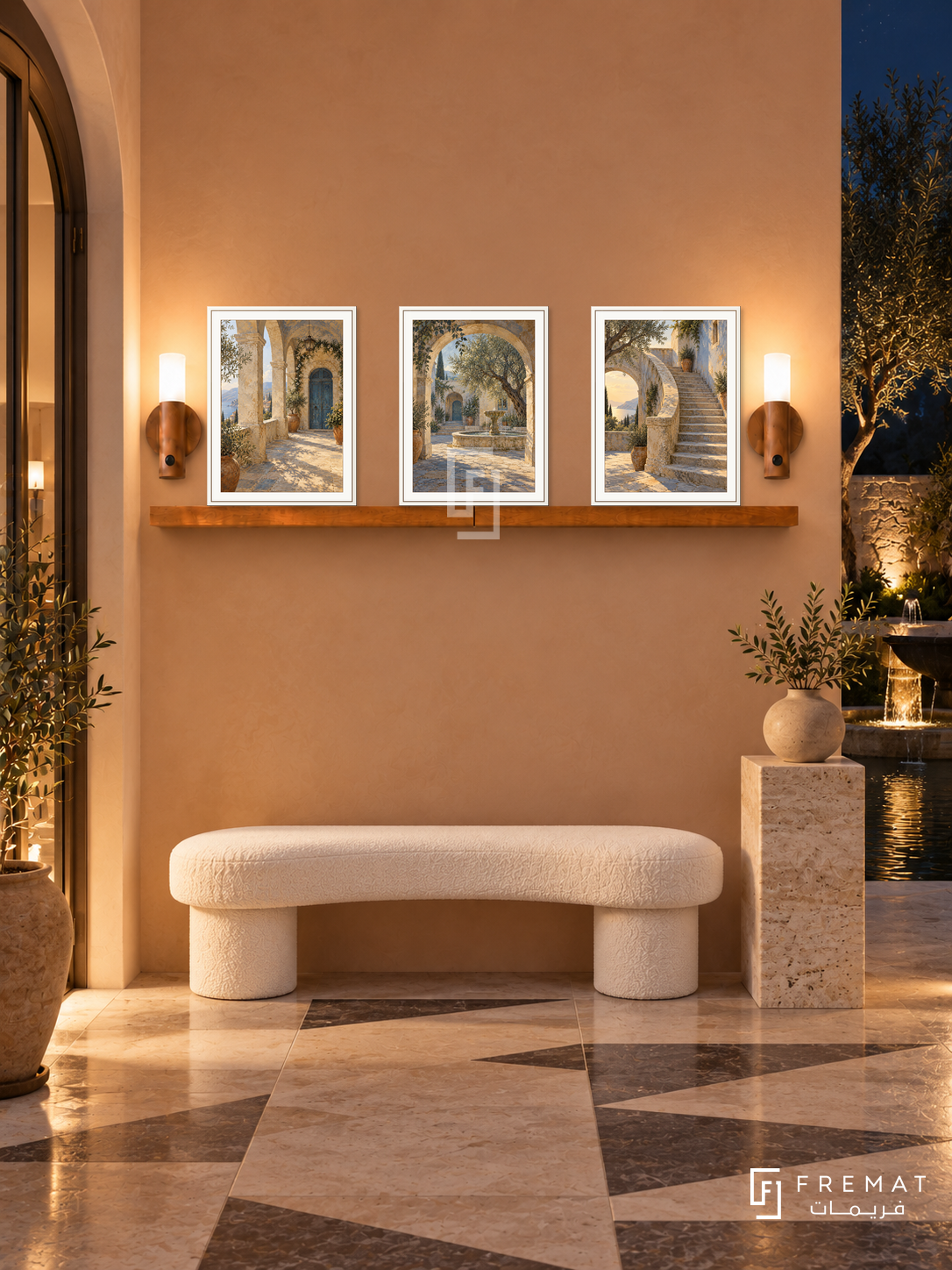 FREMAT Courtyard Journey shelf set with three 30 x 40 cm white frames, 2 cm white borders, honey wood shelf and two warm sensor lamps. Night Mediterranean entry, warm peach wall, white crescent bench, travertine pedestal, geometric stone floor, dark courtyard fountain visible right, bronze doorway left.