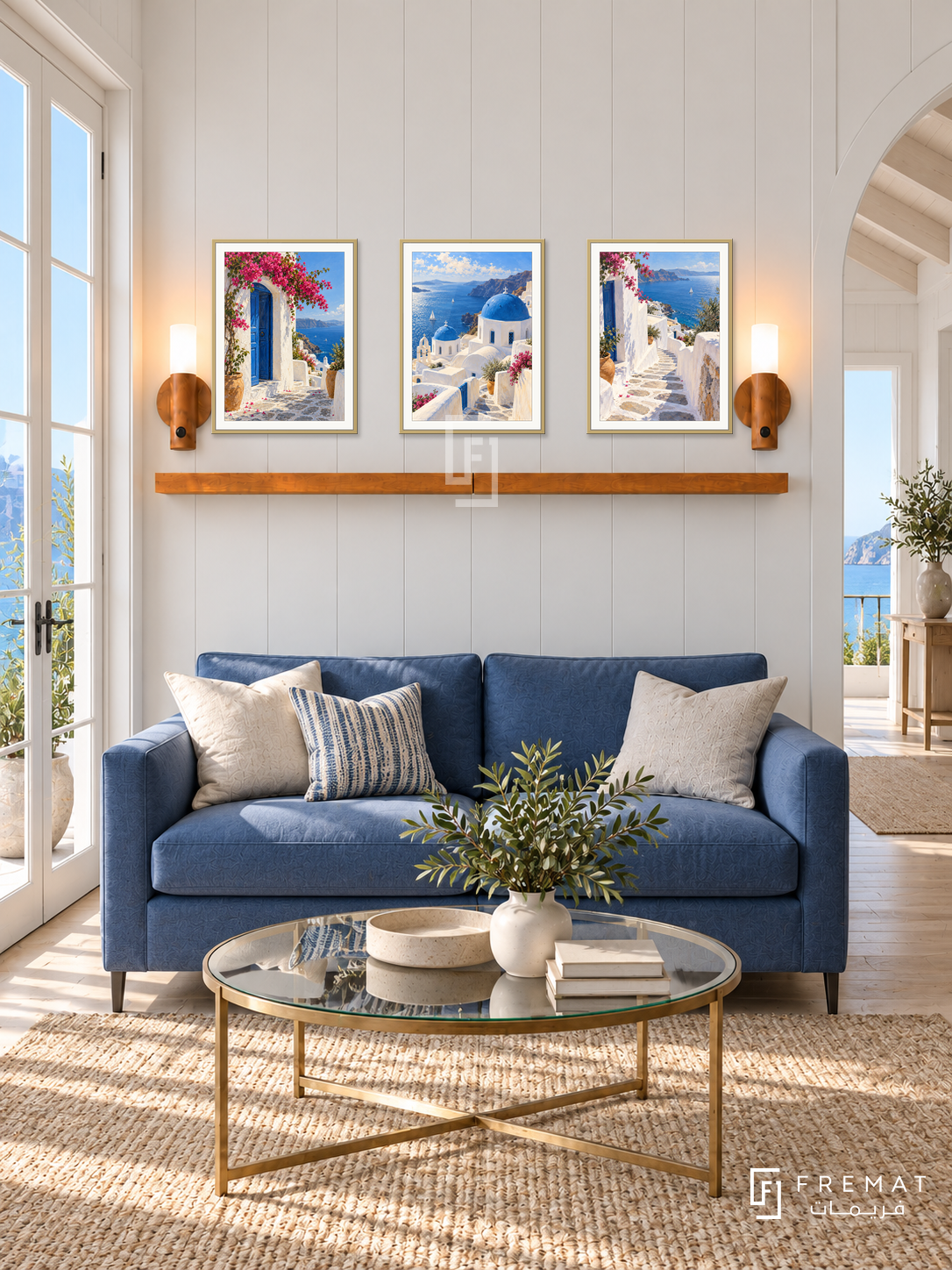 FREMAT Aegean Light shelf set with three 30 x 40 cm gold frames, 2 cm white borders, honey wood shelf and two warm sensor lamps. Morning elegant coastal salon, white panelled wall, cobalt loveseat, champagne brass glass table, pale oak floor, blue sea French doors left, vaulted opening right.