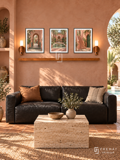 FREMAT Marrakech Rose shelf set with three 30 x 40 cm black frames, 2 cm white borders, honey wood shelf and two warm sensor lamps. Morning Marrakech modern lounge, rose plaster wall, black leather sofa, travertine cube table, terracotta floor, horseshoe courtyard arch right, narrow niche left.