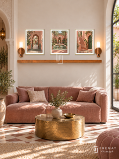 FREMAT Marrakech Rose shelf set with three 30 x 40 cm gold frames, 2 cm white borders, honey wood shelf and two warm sensor lamps. Morning elegant riad reception, pale cream wall, dusty rose velvet sofa, hammered brass round table, geometric tile floor, carved arch left, garden window right.