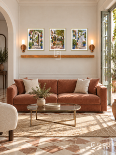 FREMAT Andalusian Patios shelf set with three 30 x 40 cm gold frames, 2 cm white borders, honey wood shelf and two warm sensor lamps. Morning refined Andalusian salon, cream wall panels, muted terracotta velvet sofa, brass glass table, patterned stone floor, garden French doors right, arch left.