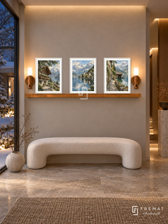 FREMAT Alpine Village shelf set with three 30 x 40 cm white frames, 2 cm white borders, honey wood shelf and two warm sensor lamps. Night alpine entrance, pale taupe wall, white curved bench, limestone pedestal, stone floor, snowy courtyard glass left, warm ceiling recess.
